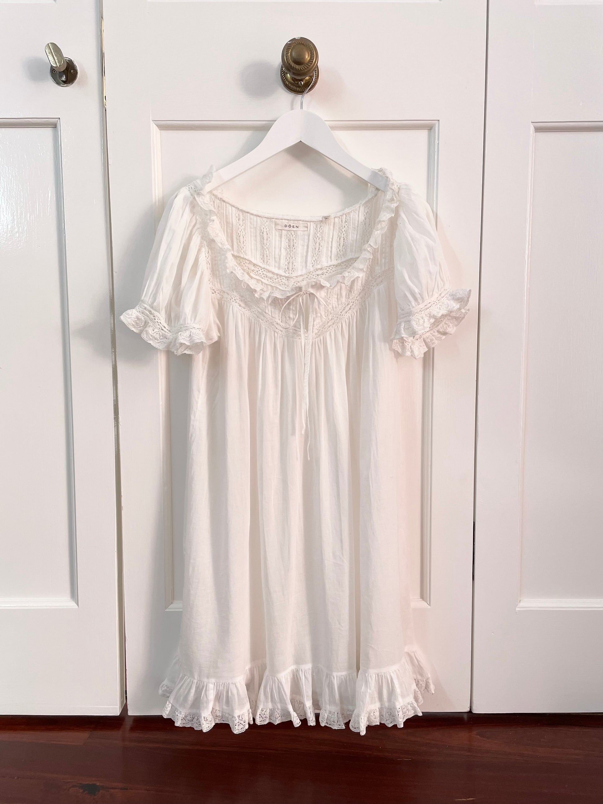 White cotton DÔEN dress with short puffed sleeves trimmed with lace and ruffles